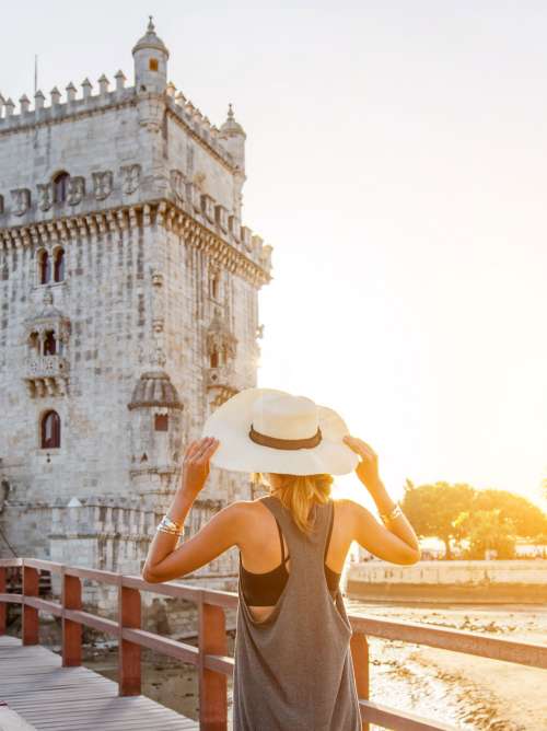 Woman wearing a hat walking towards Belém Tower in Lisbon, Portugal