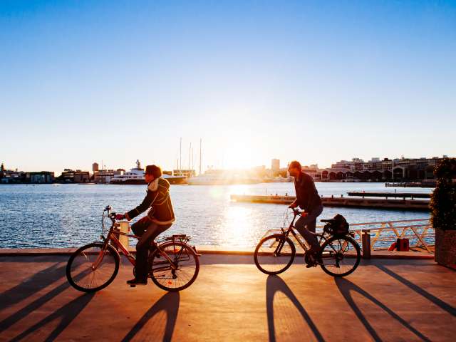 OCT 28, 2012 Valencia, Spain - Spanish Couple Cycling against sunset view at habour of La Marina de Valencia near Playa de las Arena in Valencia city; Shutterstock ID 1752901037; project: x; job: y; client: ; other: 