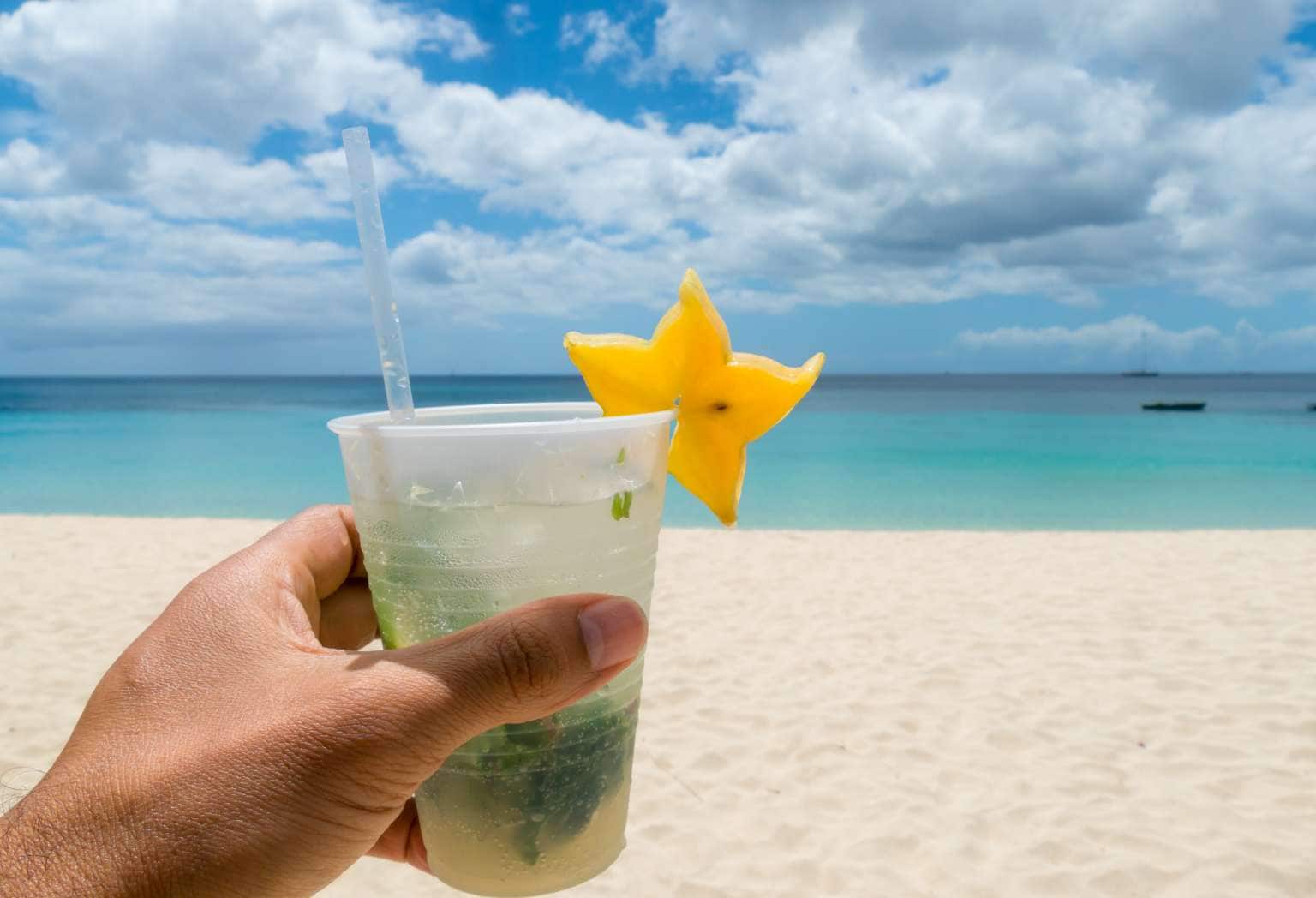 Hand holding cold mojito cocktail at the Beach of Grenada Island at the caribbean