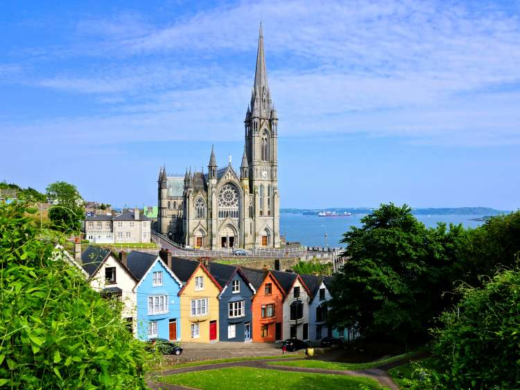 Colorful row houses with towering cathedral in background in the port town of Cobh, County Cork, Ireland