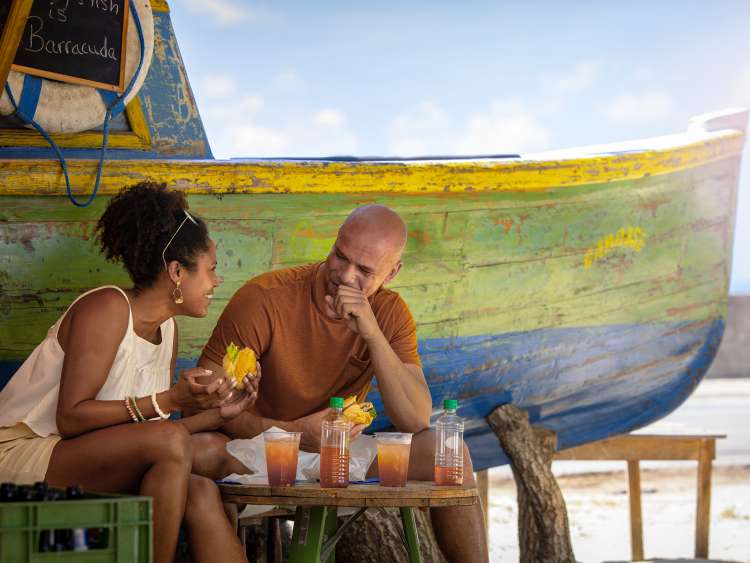 Couple enjoying drinks and food at a bar on a beach in Barbados