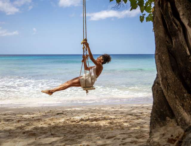 Woman sitting on swing on the beach in Barbados