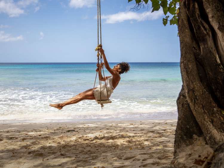 Woman sitting on swing on the beach in Barbados