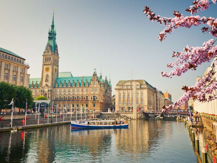A boat with passengers on the Alster (a tributary of the Elbe River) next to the Hamburg City Hall