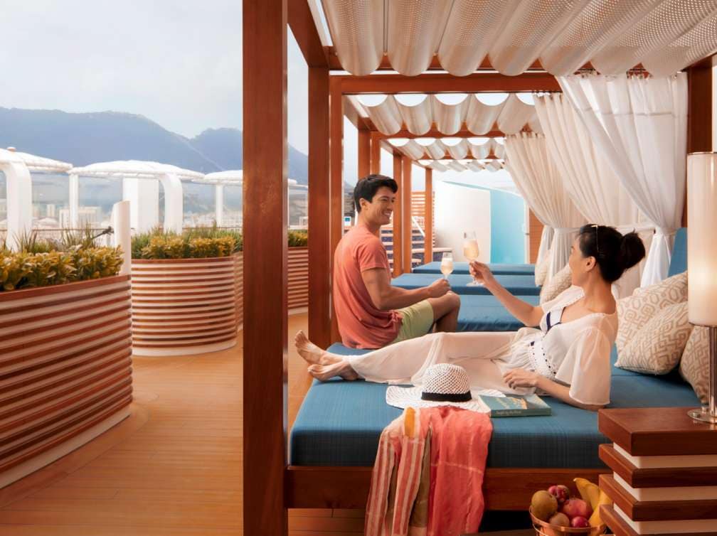 Couple enjoying a drink on a sunbed in The Retreat on P&O Cruises ship Iona