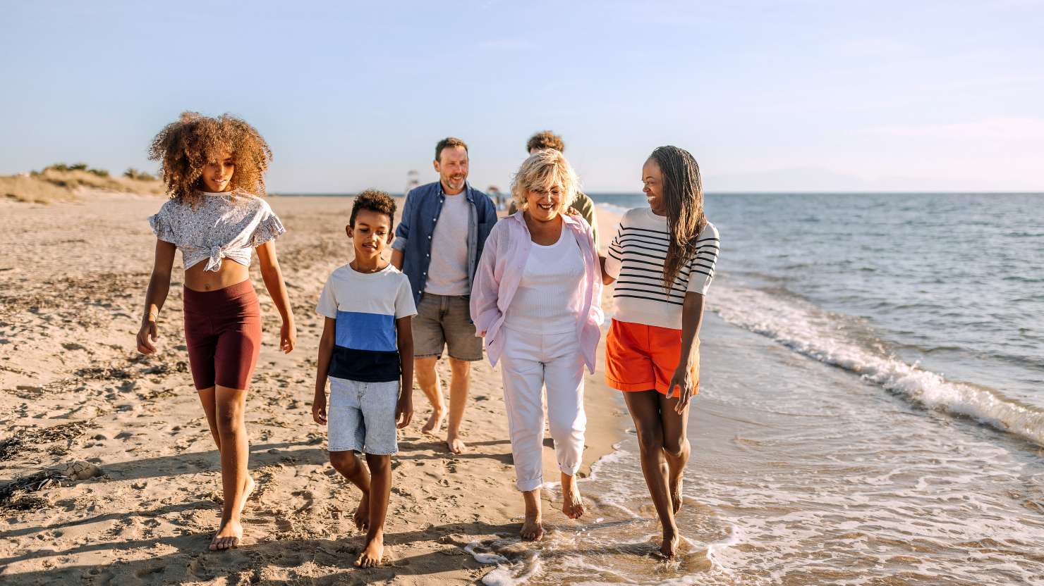 Multiracial family walking on the beach together, having fun and talking