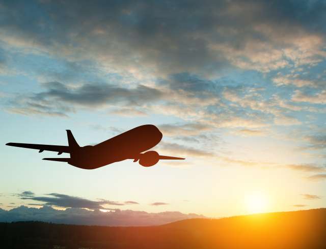 Airplane taking off at the sunset sky. Silhouette of aircraft in the sky.