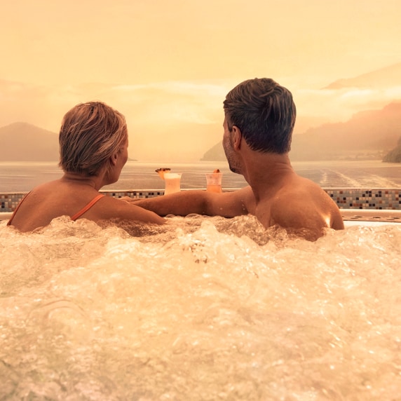 Couple in hot tub looking out to sea 