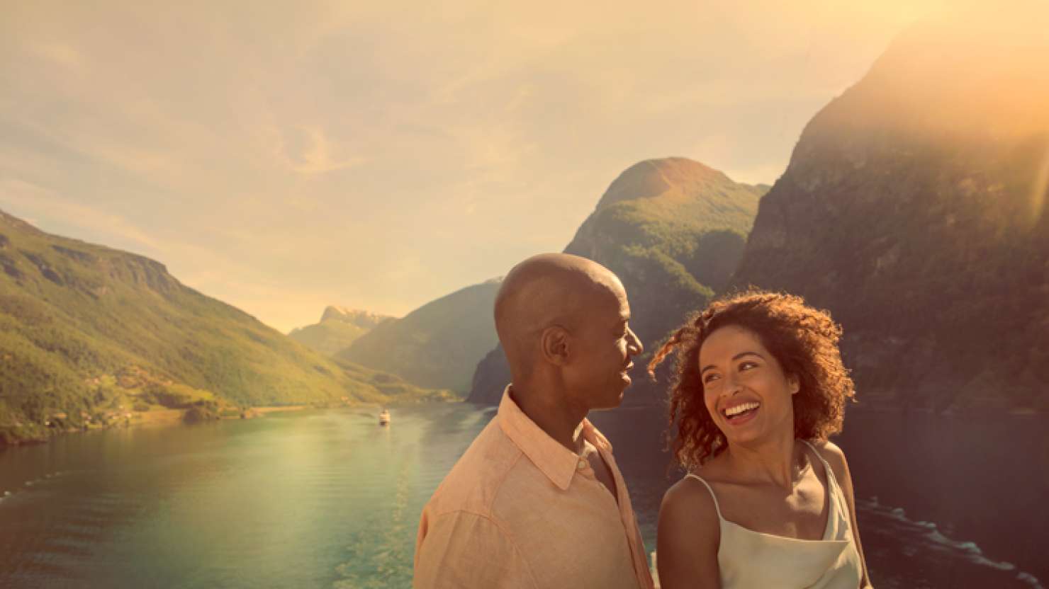 Couple laughing on deck in front of mountains