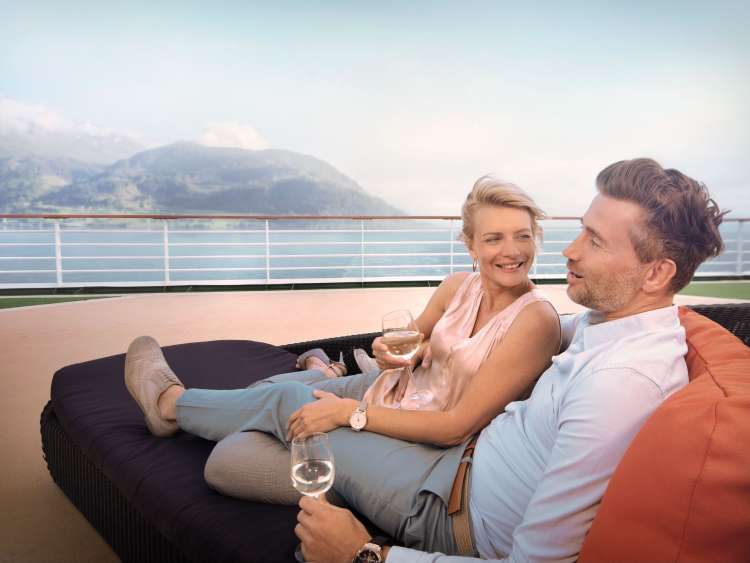 Couple drinking wine on a sun lounger on deck on a P&O Cruises cruise ship