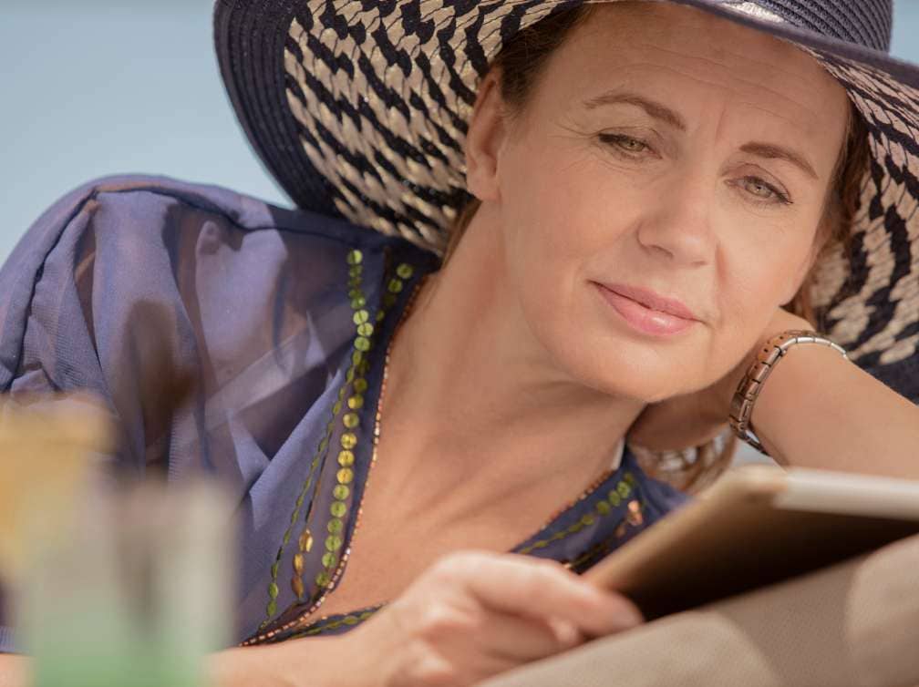  Lady in sun hat reading a book on deck