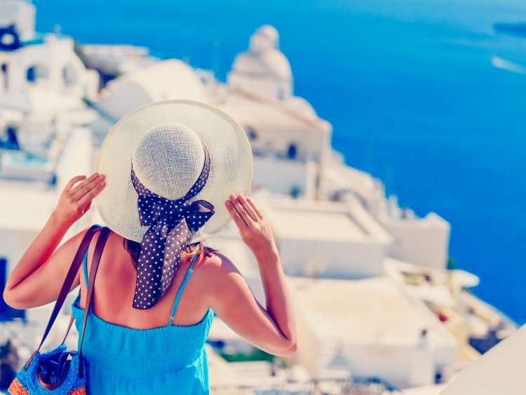 Lady with hat looking over Santorini in Greece