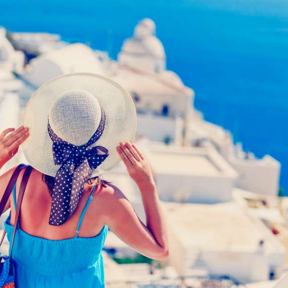Lady with hat looking over Santorini in Greece