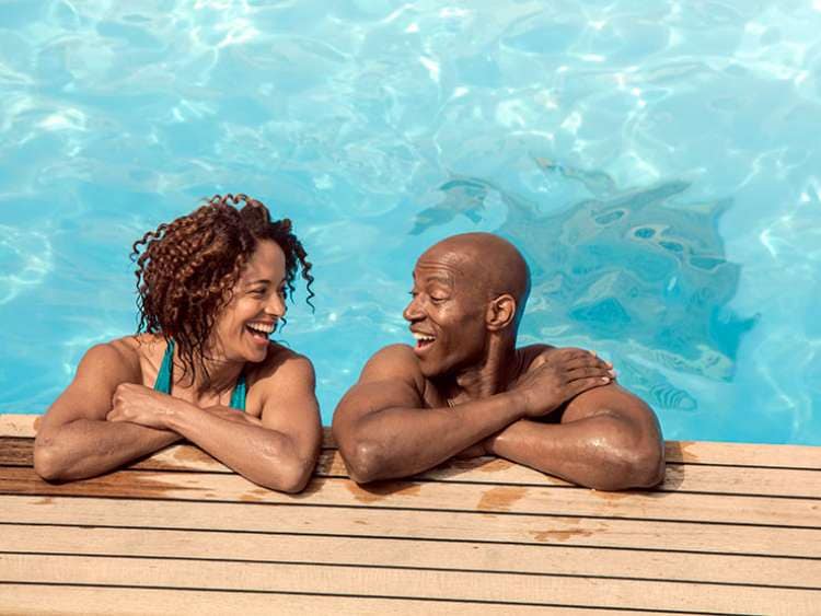 Couple laughing together at side of the pool