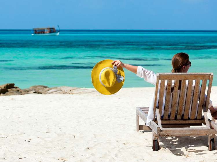 Couple chatting on deck chairs on beach looking out to sea