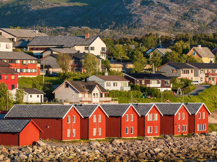 Red houses facades reflecting on the bay of Alta, Norway;