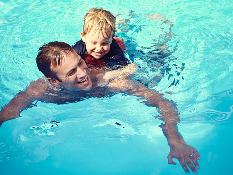 Man and boy swimming in the pool on-board