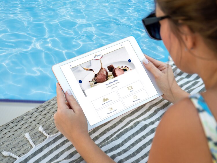 Woman sat by pool looking at My Holiday on her Ipad