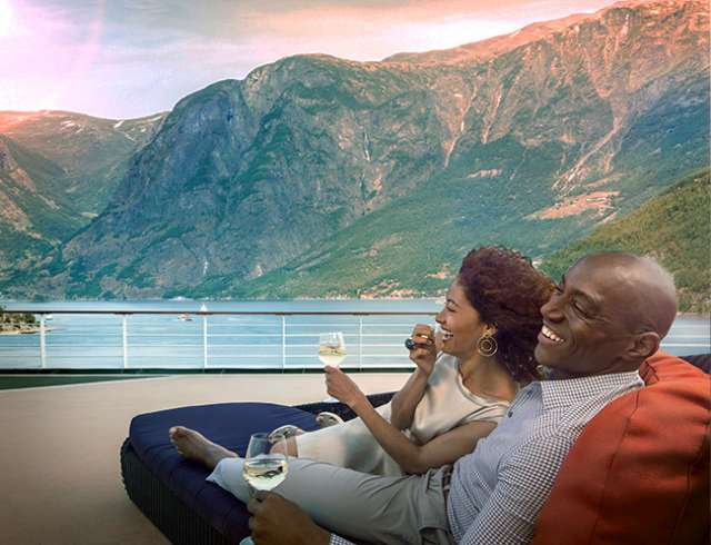 Couple sat on sunbed looking at mountains on Norwegian fjords cruise 