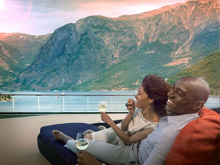 Couple sat on sunbed looking at mountains on Norwegian fjords cruise 