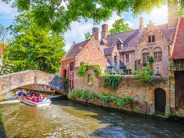 Tourists sat in boat going along river under a bridge 