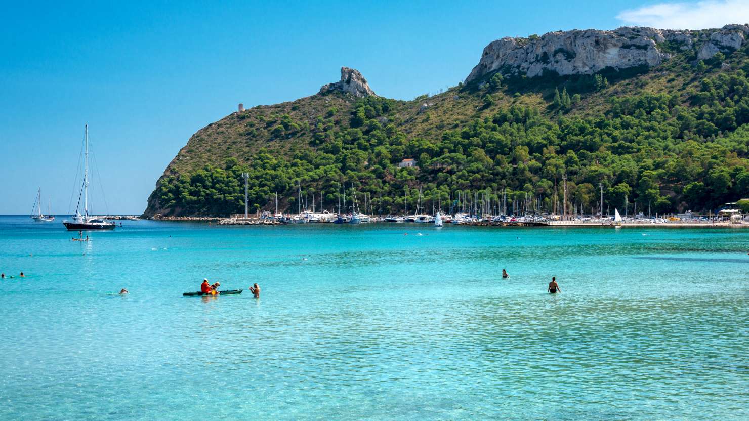 Poetto beach, crystal clear water and the famous Sella del Diavolo, Cagliari, Sardinia, Italy