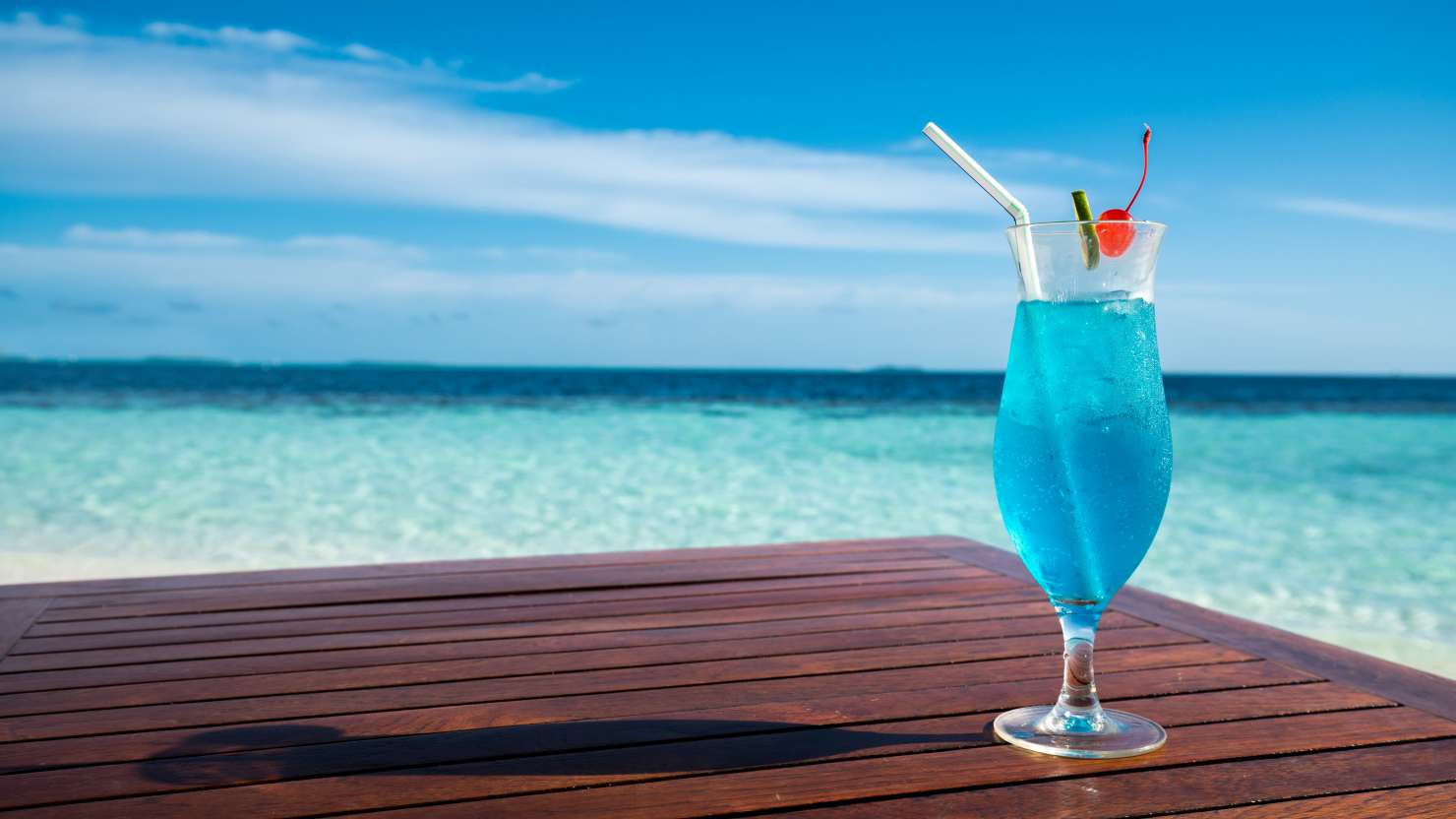 Blue lagoon cocktail on table and beautiful sea background; Shutterstock ID 1276004458; purchase_order: -; job: -; client: -; other: