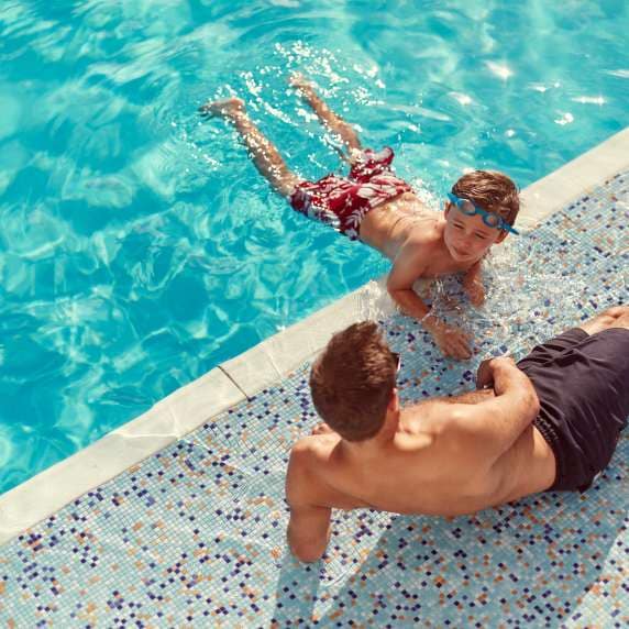 Man and boy by the side of the swimming pool