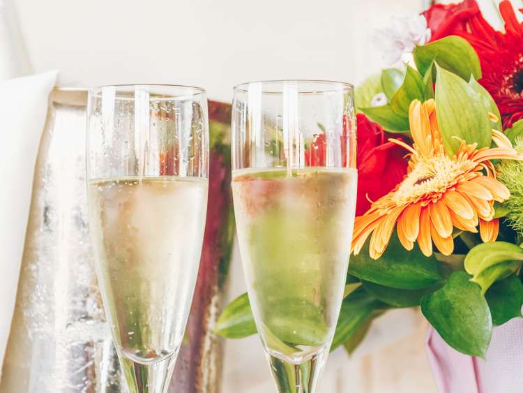 Two glasses of bubbly near a bouquet of flowers