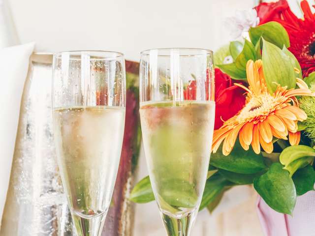 Two glasses of bubbly near a bouquet of flowers