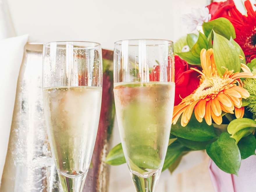 Two glasses of bubbly near a bouquet of flowers
