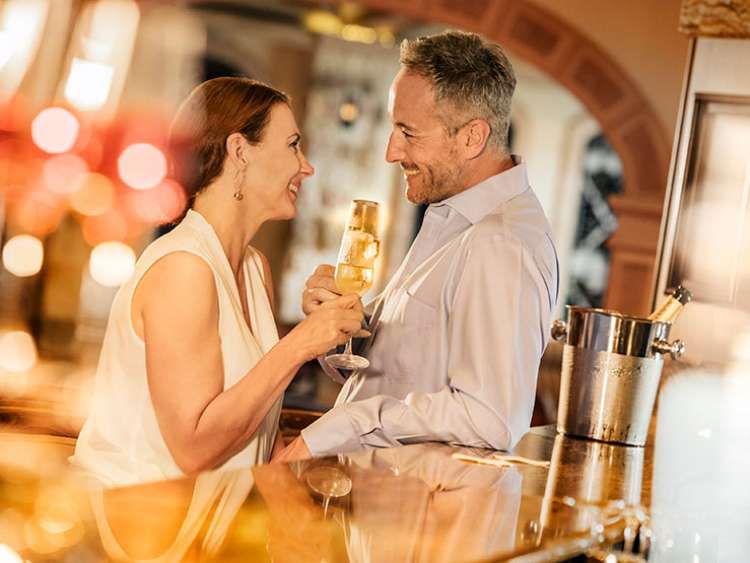 Couple chatting to each other holding drinks 