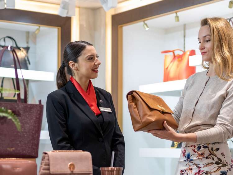 Sales assistant helping out passengers with a purchase on board a P&O Cruises shop