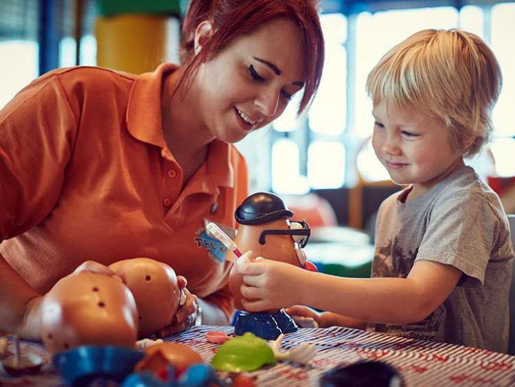 Holiday rep playing with toys with child in the kids club 