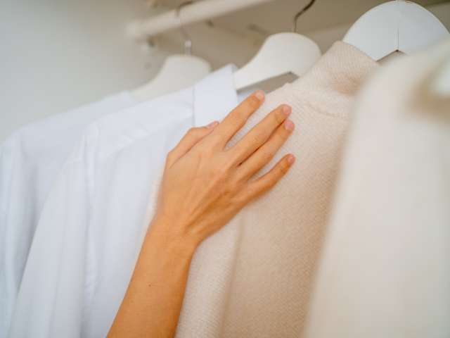 Cropped hands choosing new clothes, shirts and sweaters outfit for the day. Close up