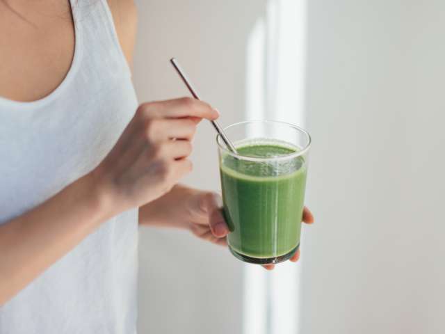Cropped shot of young woman drinking vegan smoothie with metal straw.