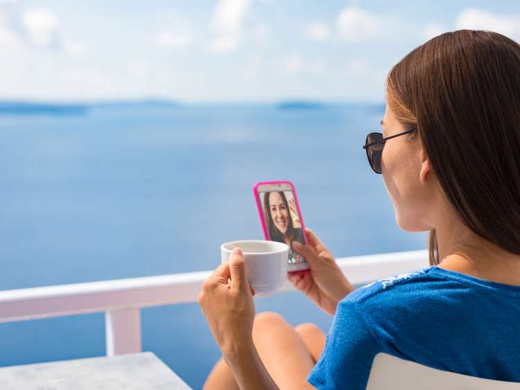 Women drinking a cup of tea on facetime to her friend on deck