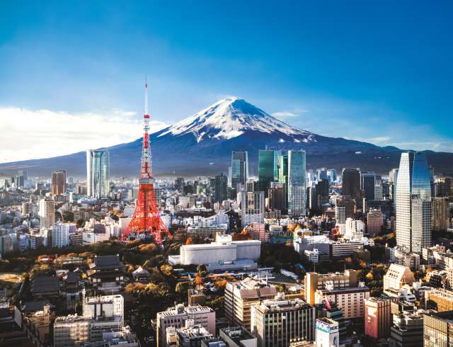 Aerial view of Mt. Fuji, Tokyo Tower and modern skyscrapers in Tokyo on a sunny day.