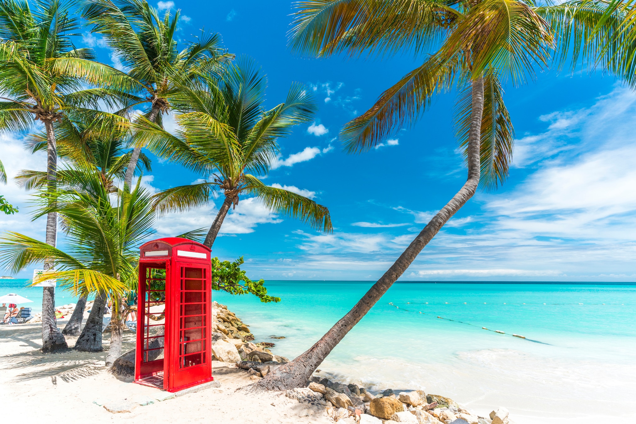 Iconic red british phone box in front of the clear Caribbean Sea, Siboney Beach, Dickenson Bay, Antigua