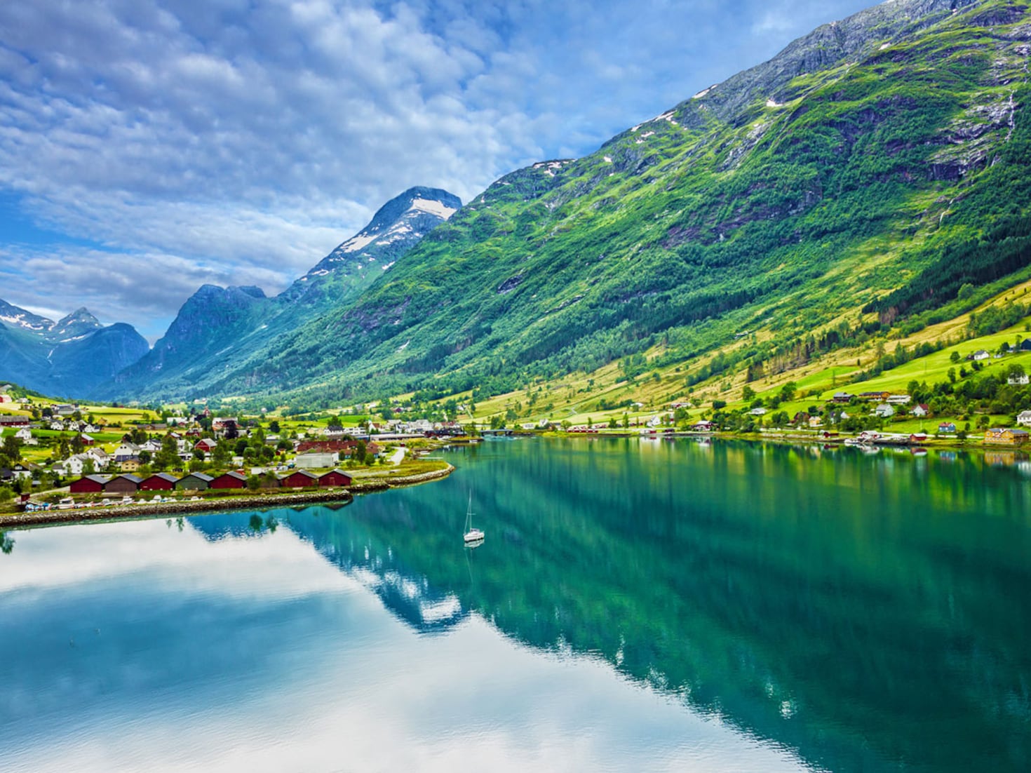 {"metadata_en_GB":{"alt-text":" Big green mountains next to water and houses "},"metadata_en_AU":{"alt-text":" Big green mountains next to water and houses "}}