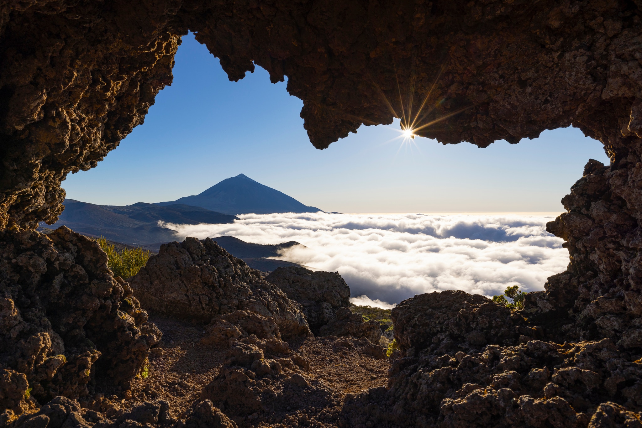a small cave frames the majestic Teide Volcano during a beautiful sunny day, Tenerife, Canary Island, Spain, Europe
