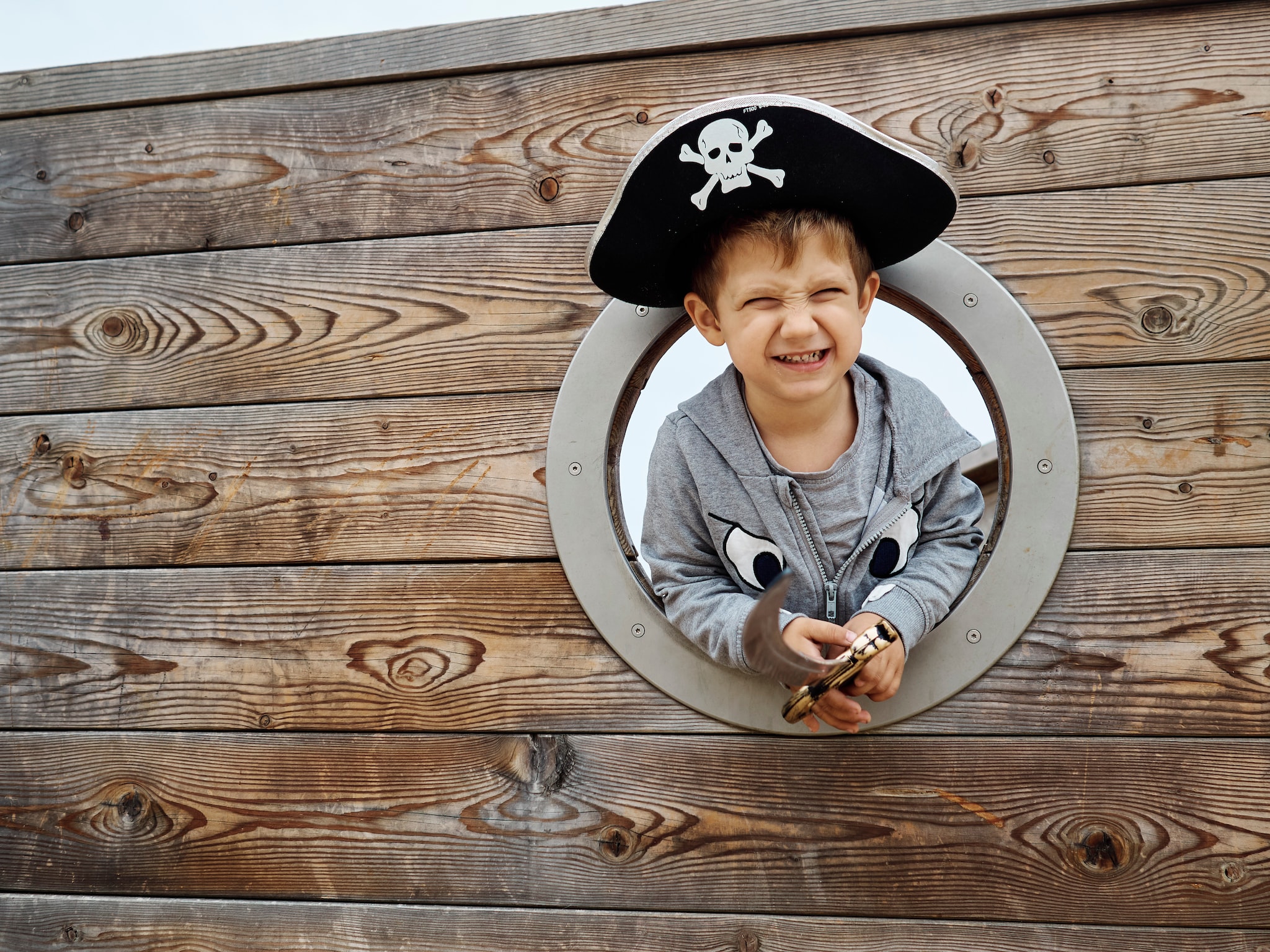 Little boy wearing a pirate hat and smiling inside a pirate ship and holding a sword. Childhood concept
