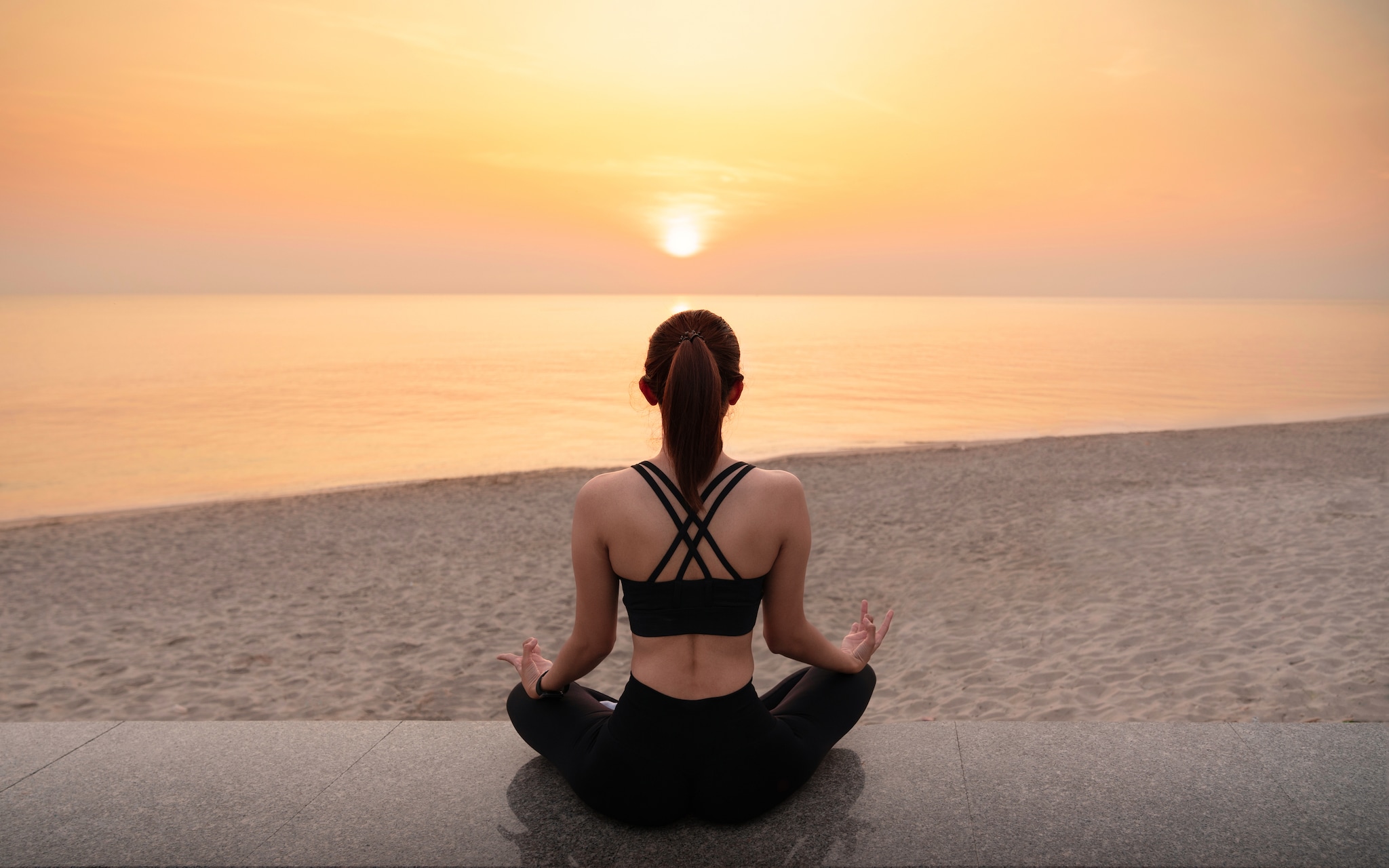 Young healthy woman practicing yoga on the beach at sunset. Body of beautiful girl in a meditation on the beach. Lifestyle woman yoga exercise and pose for healthy life. Welness background. Spa concept.