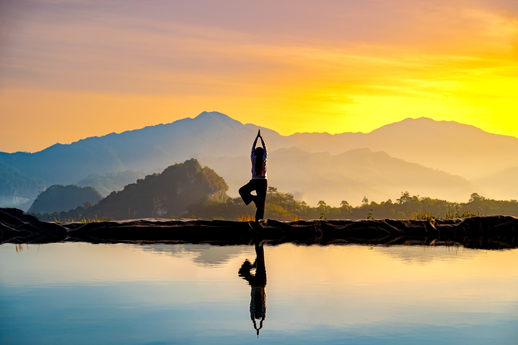 {"metadata_en_GB":{"alt-text":"Woman practicing stretching On the high mountain slopes in the morning mist and by the reflection ponds"}}