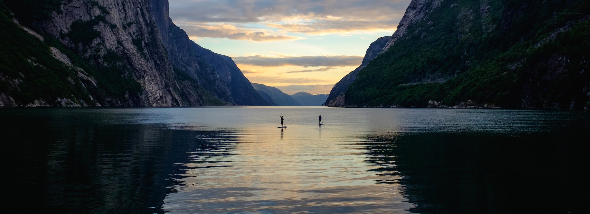 Two people paddle boarding in the Norwegian Fjords