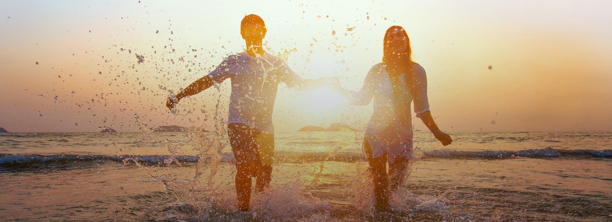 {"metadata_en_GB":{"alt-text":"Couple running in sea together holding hands"},"metadata_en_AU":{"alt-text":"Couple running in sea together holding hands"}}