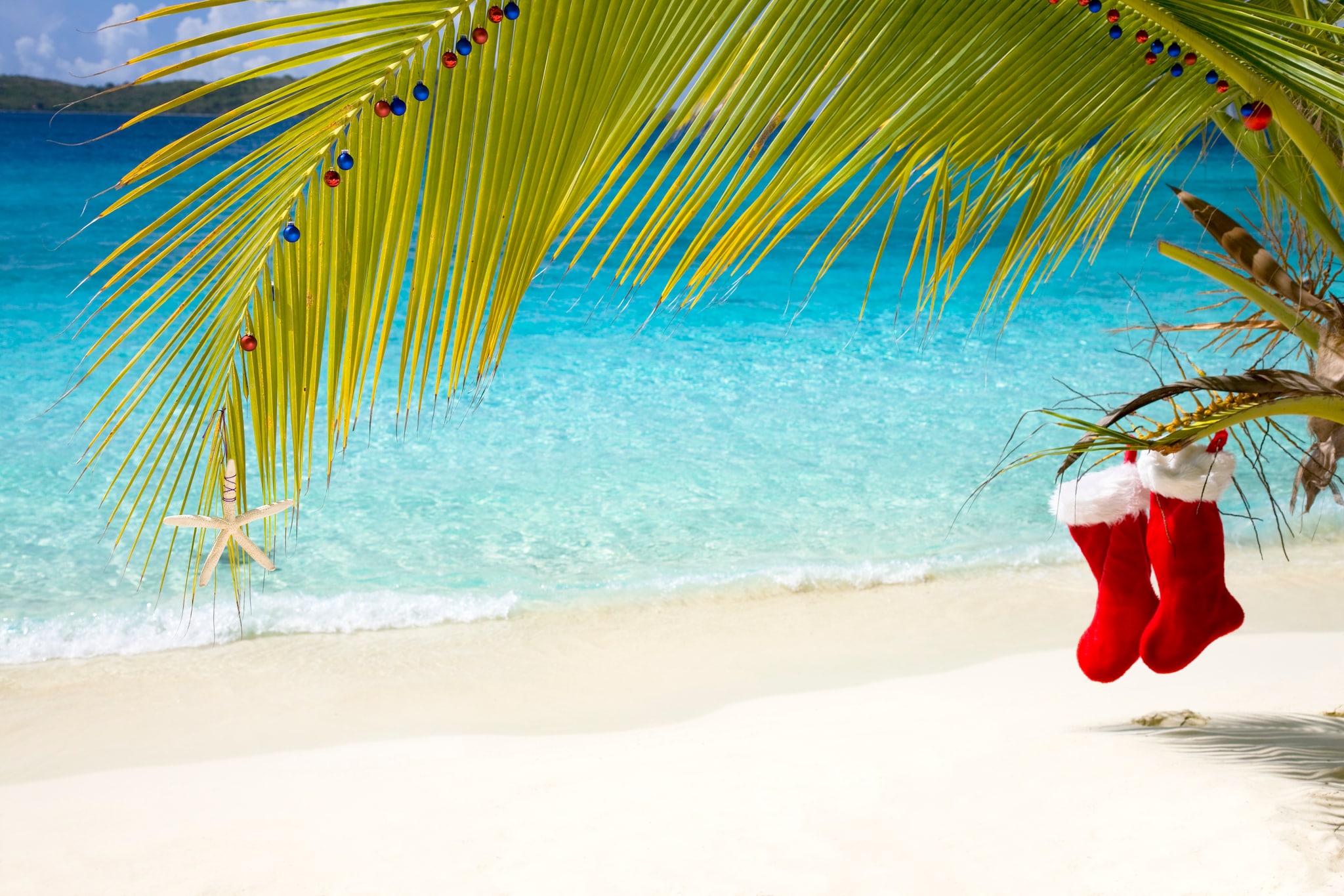 {"metadata_en_GB":{"alt-text":"tropical Christmas on the beach in the Caribbean with two Santa Claus stockings"}}