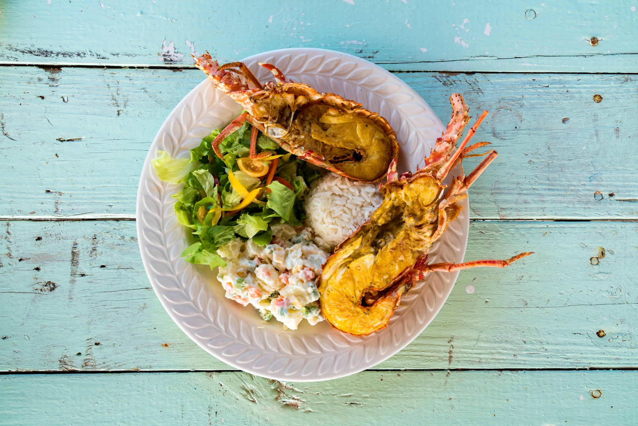 Dish with fresh lobster with rice and vegetables on wood table background, Caribbean
