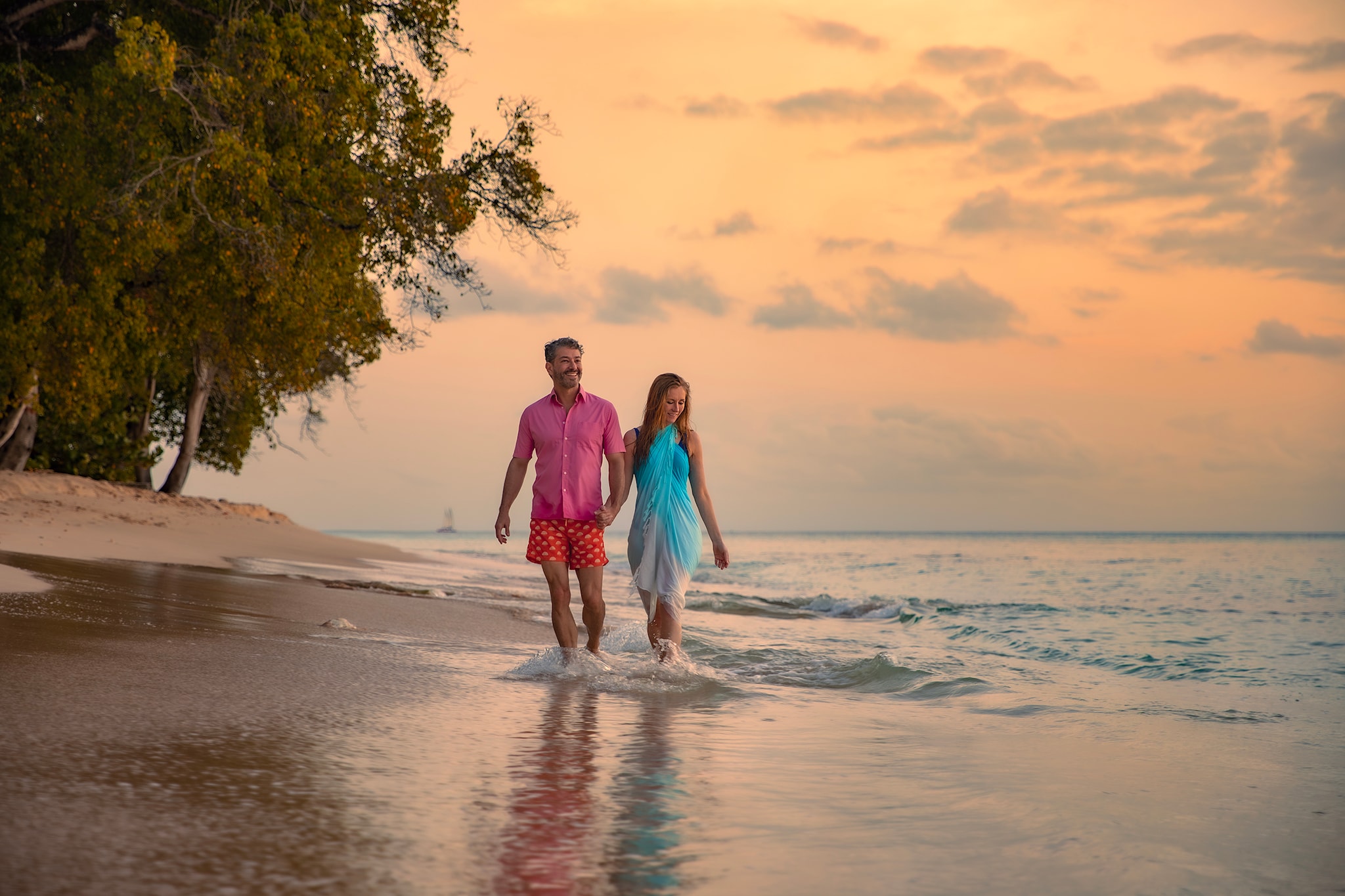 {"metadata_en_GB":{"alt-text":"Couple walking along a beach in Barbados with the tide coming in"}}