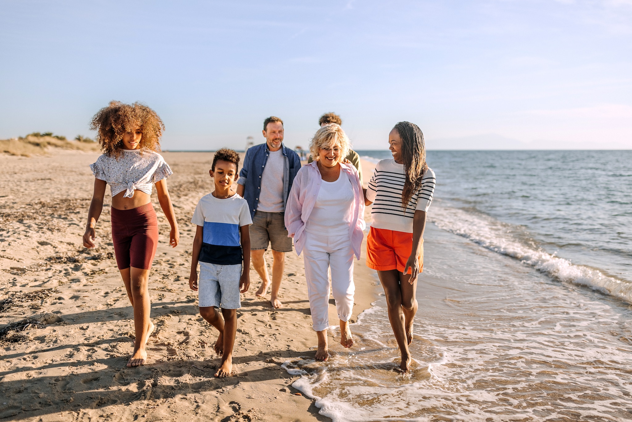 Multiracial family walking on the beach together, having fun and talking